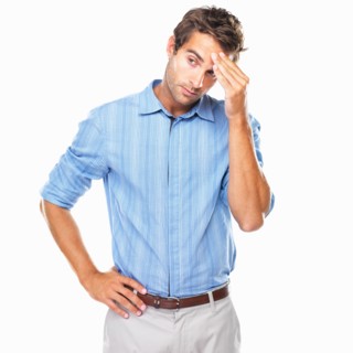 Young business man standing with hand on forehead and looking away. Photo : momentimages