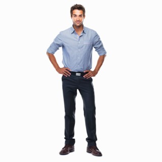 Portrait of young business man standing with hands on hips and smiling against white background.