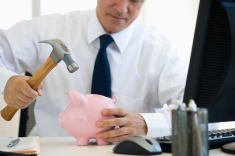 Businessman hammering piggy bank.