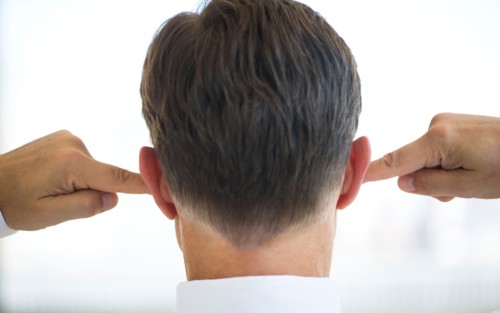 Businessman plugging ears.