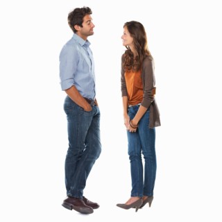 Studio shot of young couple standing face to face and smiling. Photo : momentimages