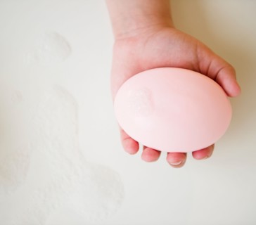 Close up of girl's (8-9) hand holding soap bar. Photo: Jamie Grill