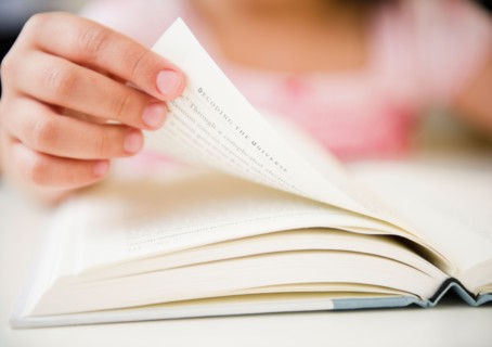Close up of girl's (8-9) hand turning pages. Photo: Jamie Grill