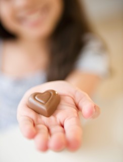 Close up of girl's (10-11) hand holding chocolate heart. Photo : Jamie Grill