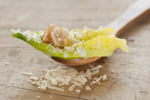 Fresh caesar salad on wooden spoon.