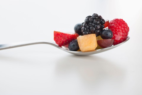 Fresh fruit salad on spoon.