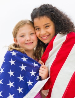 Portrait of girls (8-9) wrapped in US flag.