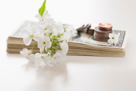 Flowers and coins on pile of dollar bills.