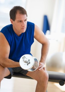 Mature man lifting weights in gym.