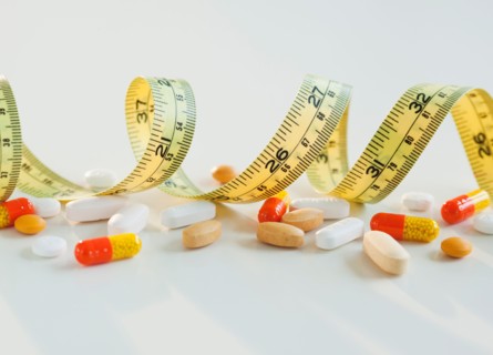 Tape measure, pills and capsules, studio shot. Photo : Jamie Grill