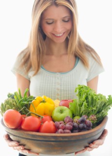 Woman holding bowl of organic fruit and vegetables.