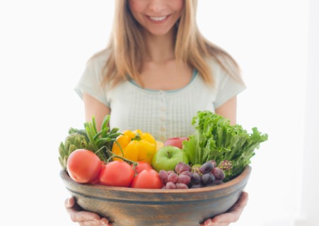 Woman holding bowl of organic fruit and vegetables.