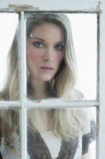 Portrait of young woman looking through window.