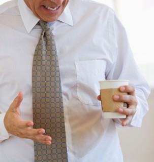 Businessman spilling coffee on shirt.