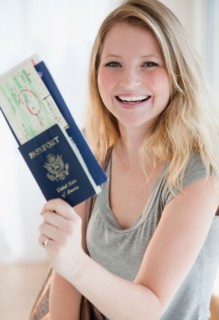 Young woman holding passports and plane tickets. Photo : Jamie Grill