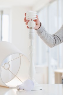 Woman changing classic bulb to energy efficient bulb. Photo : Jamie Grill