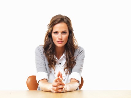 Portrait of attractive business woman sitting at table with hands clasped. Photo : momentimages