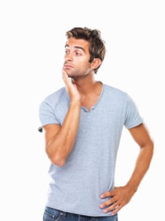 Studio shot of thoughtful young man with hand on chin. Photo : momentimages