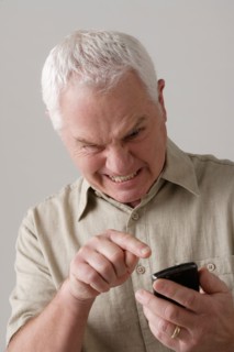 Portrait of angry senior man with mobile phone, studio shot. Photo : Rob Lewine
