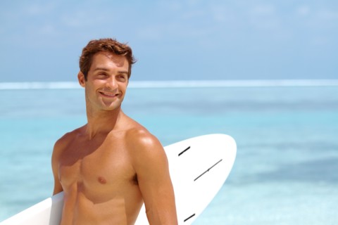 Shirtless young man holding surfboard. Photo : momentimages