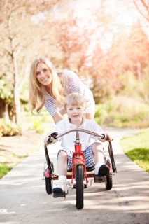 Mother and son (2-3) riding tricycle in park. Photo: Take A Pix Media