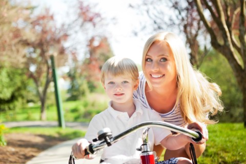 Mother and son (2-3) riding tricycle in park. Photo: Take A Pix Media