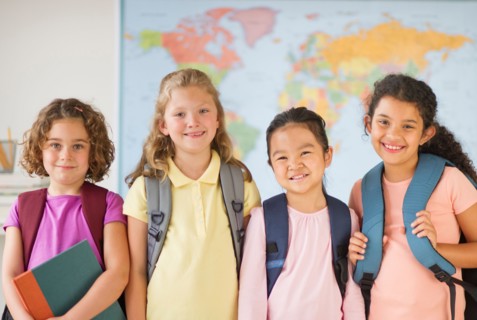 Portrait of four girls (6-9) carrying backpacks.
