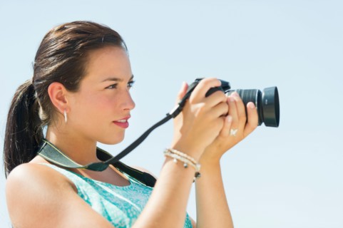 Portrait of young woman taking pictures with camera.