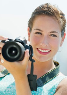 Portrait of young woman taking pictures with camera.