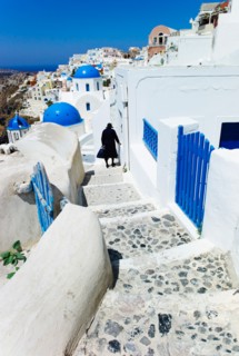 Greece, Cyclades Islands, Santorini, Oia, Woman walking down steps in town.