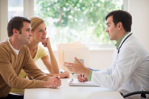 Couple receiving advice from doctor in office.