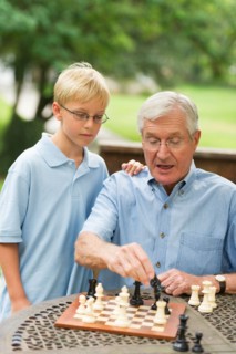 Grandfather teaching grandson (10-11) how to play chess.