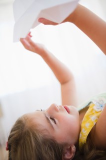 Girl ( 6-7) playing with paper plane. Photo : Jamie Grill