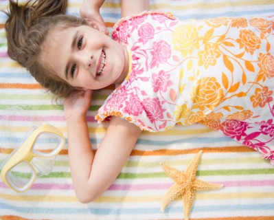 Smiling girl ( 6-7) lying on towel on vacations. Photo : Jamie Grill