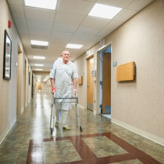 Senior man in hospital walking with walker.
