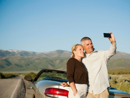 Mid adult couple photographing themselves in front of majestic mountain range.