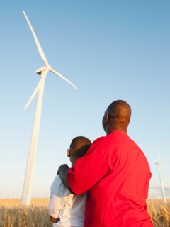 USA, Oregon, Wasco, Father and son (8-9) standing in wheat field, watching wind turbine.