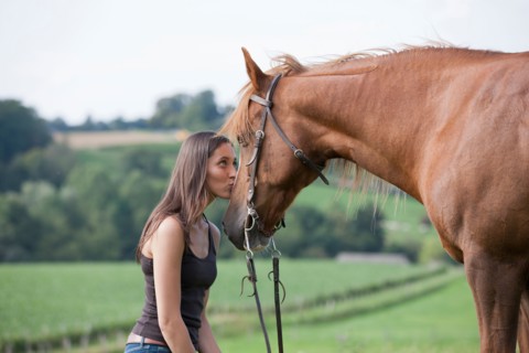 Young woman kissing horse in field. Photo : Jan Scherders
