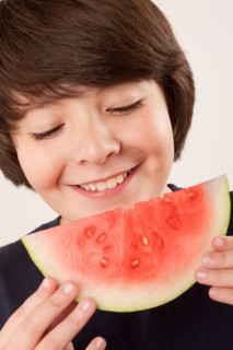 Studio portrait of boy (10-11) eating watermelon. Photo : Rob Lewine