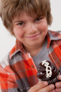 Studio portrait of boy (8-9) holding cake. Photo : Rob Lewine