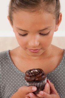 Studio portrait of girl (8-9) holding cake. Photo : Rob Lewine