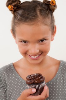 Studio portrait of girl (8-9) holding cake. Photo : Rob Lewine