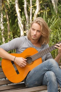 Young man playing guitar in park. Photo : Rob Lewine
