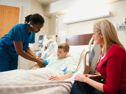 Nurse checking blood pressure to boy (10-11), mother is sitting next to bed. Photo: Erik Isakson