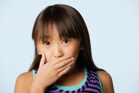 Studio portrait of girl (10-11) covering mouth with hand. Photo : Rob Lewine