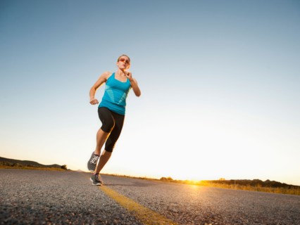 Mid adult couple running on empty road.