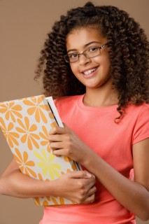 Studio portrait of girl (10-11) holding book. Photo : Rob Lewine