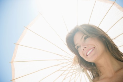 Woman in sunlight with parasol. Photo : Jamie Grill