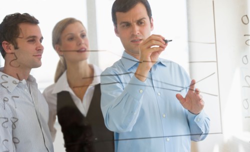 Businessman writing on transparent board.