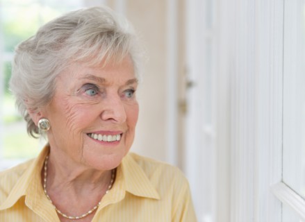 Portrait of senior woman looking through window.